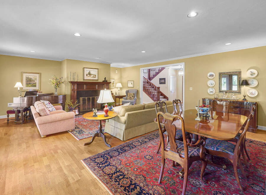 This spacious living and dining area features a beautiful grand piano, a cozy fireplace, and a formal dining set perfect for entertaining.