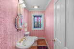 Step into this charming powder room featuring elegant pink damask wallpaper and a decorative stained-glass window that adds a touch of vintage flair.