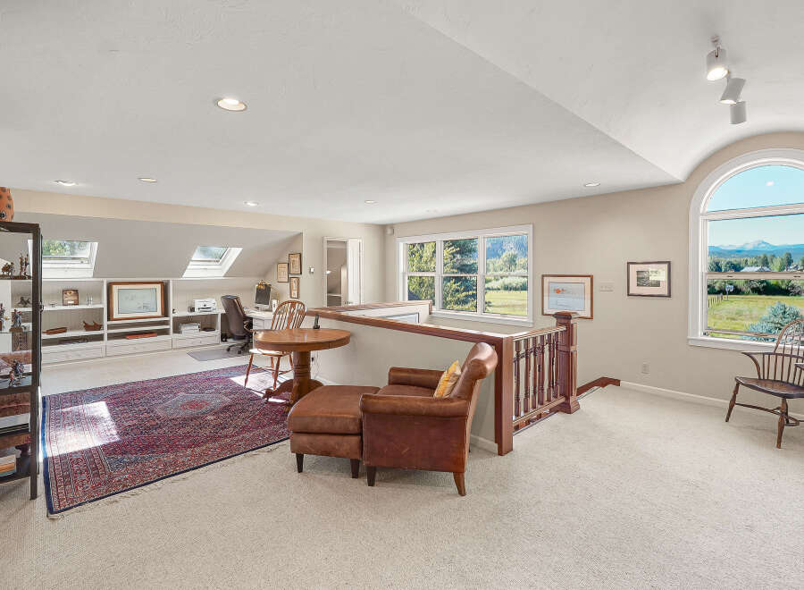 This spacious loft area offers a versatile living space with a dedicated office nook featuring built-in shelving and a comfortable desk setup.