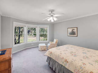 This charming bedroom features a comfortable bed with a floral comforter and a matching armchair with an ottoman, perfect for relaxation.