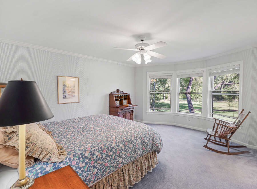 This charming bedroom features a comfortable bed with a floral comforter and a decorative bed skirt.