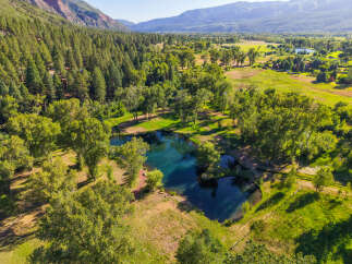 Discover this stunning property featuring a crystal-clear blue spring-fed pond, surrounded by lush green trees and rolling hills.
