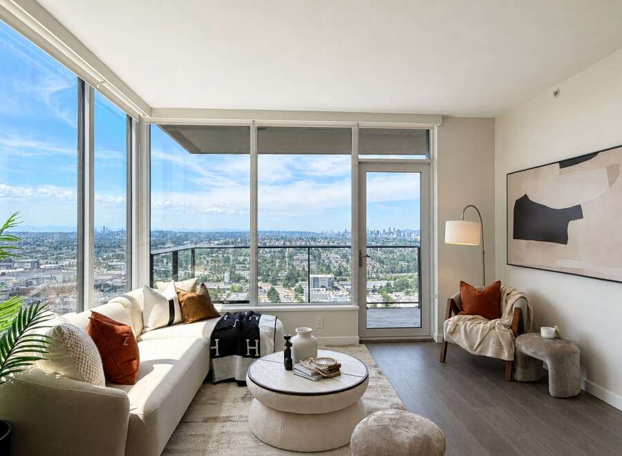 Experience breathtaking city and mountain views from this stunning living room, featuring expansive floor-to-ceiling windows that flood the space with natural light.