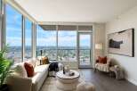 Experience breathtaking city and mountain views from this stunning living room, featuring expansive floor-to-ceiling windows that flood the space with natural light.