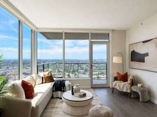 Experience breathtaking city and mountain views from this stunning living room, featuring expansive floor-to-ceiling windows that flood the space with natural light.