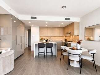 Experience modern living in this stunning open-concept condo, featuring a sleek, integrated kitchen with high-end appliances and ample cabinet space.