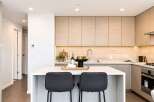 Experience modern living in this stunning kitchen featuring sleek, light wood cabinetry and a spacious white island perfect for entertaining.