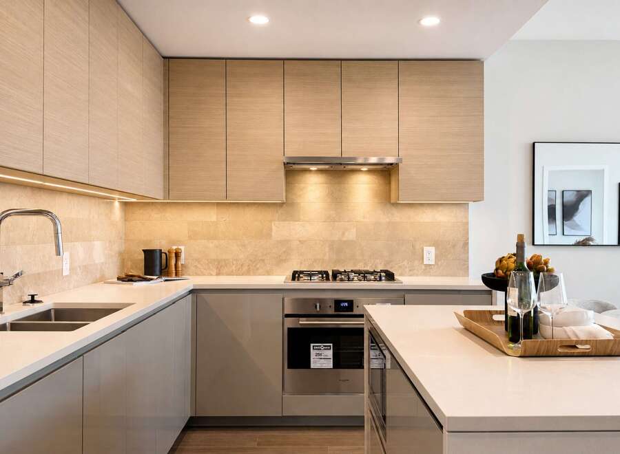 Experience modern luxury in this stunning kitchen, featuring sleek, light wood cabinetry and a sophisticated stone tile backsplash.