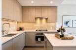 Experience modern luxury in this stunning kitchen, featuring sleek, light wood cabinetry and a sophisticated stone tile backsplash.