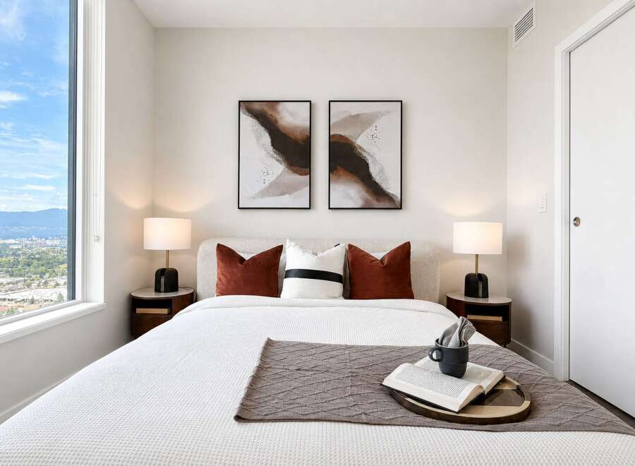 Experience modern comfort in this beautifully appointed bedroom, featuring a plush bed, elegant bedside tables with lamps, and captivating abstract art.