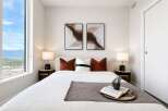 Experience modern comfort in this beautifully appointed bedroom, featuring a plush bed, elegant bedside tables with lamps, and captivating abstract art.