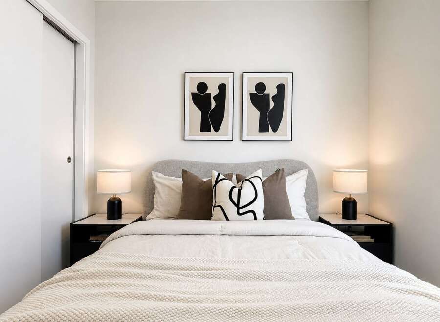 This modern bedroom features a plush upholstered headboard and a comfortable bed adorned with decorative pillows.
