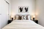 This modern bedroom features a plush upholstered headboard and a comfortable bed adorned with decorative pillows.