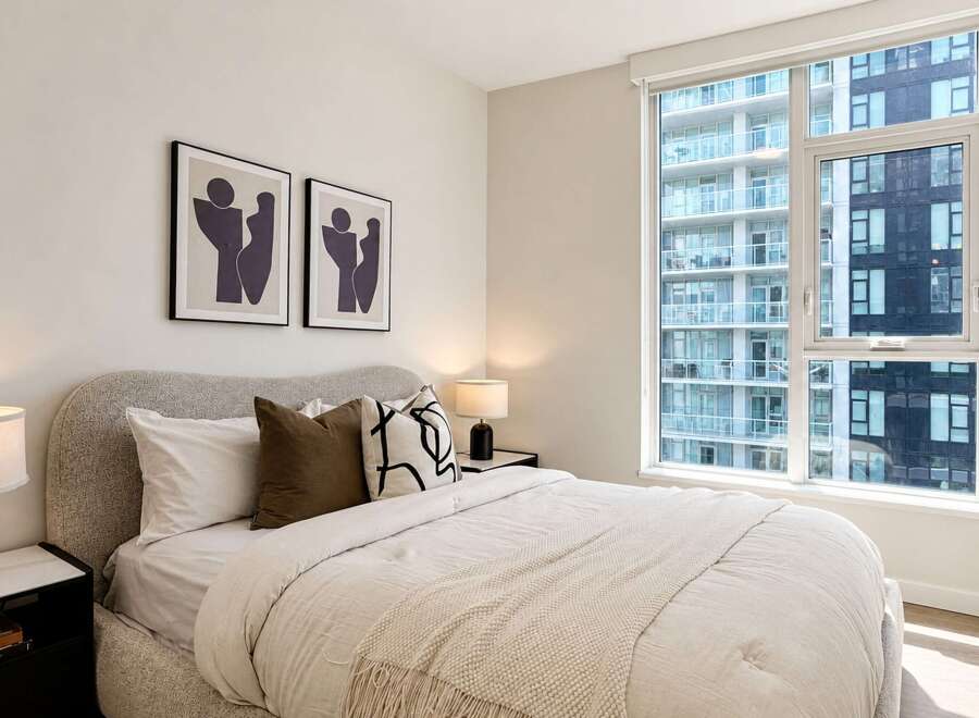 Experience modern urban living in this stylish bedroom, featuring a comfortable bed adorned with plush pillows and a textured throw.