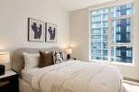 Experience modern urban living in this stylish bedroom, featuring a comfortable bed adorned with plush pillows and a textured throw.
