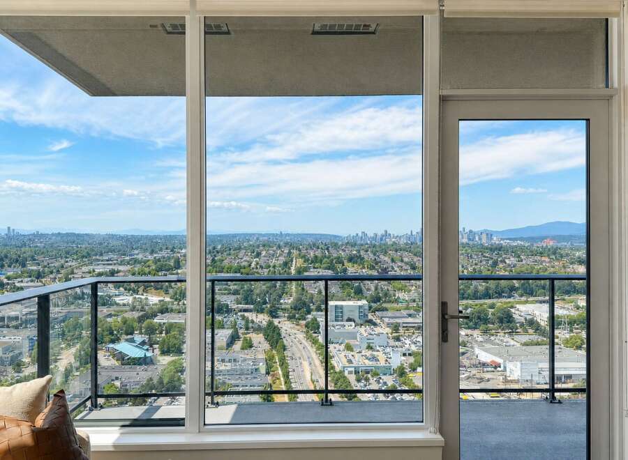 Experience breathtaking panoramic views from this stunning property, featuring expansive windows and a private balcony overlooking a vibrant cityscape.