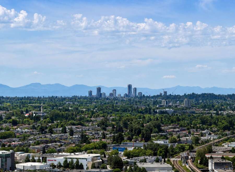 Experience the vibrant urban landscape with this stunning panoramic view, showcasing a bustling cityscape nestled amidst lush greenery and majestic mountains.