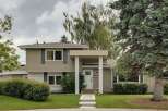 Charming two-story home featuring a welcoming covered porch with white columns and a bright white front door.