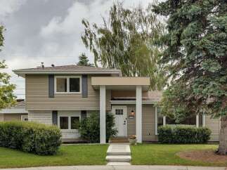 Charming two-story home featuring a welcoming covered porch with white columns and a bright white front door.