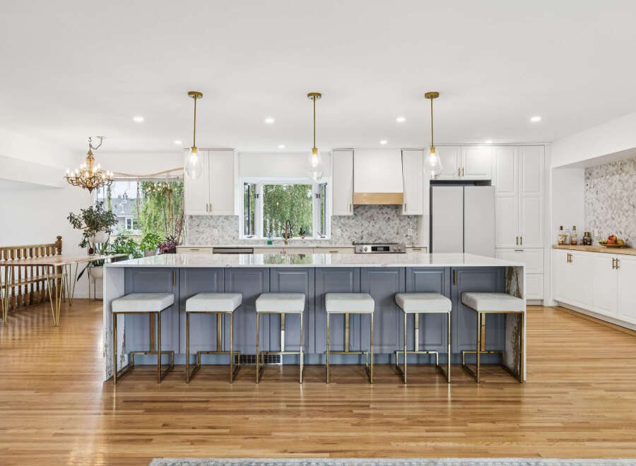 This stunning kitchen boasts a large island with grey cabinetry and white bar stools, perfect for casual dining and entertaining.