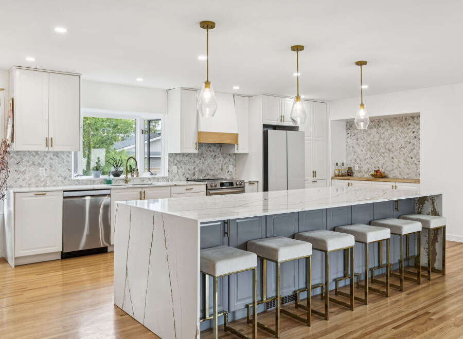 Experience luxury in this stunning modern kitchen, featuring a spacious island with a waterfall quartz countertop and comfortable bar seating.