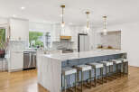 Experience luxury in this stunning modern kitchen, featuring a spacious island with a waterfall quartz countertop and comfortable bar seating.