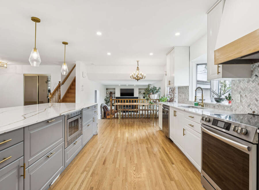 Experience modern living in this stunning open-concept kitchen and dining area, featuring sleek white cabinetry, a large island with a quartz countertop, and a sophisticated herringbone tile backsplash.