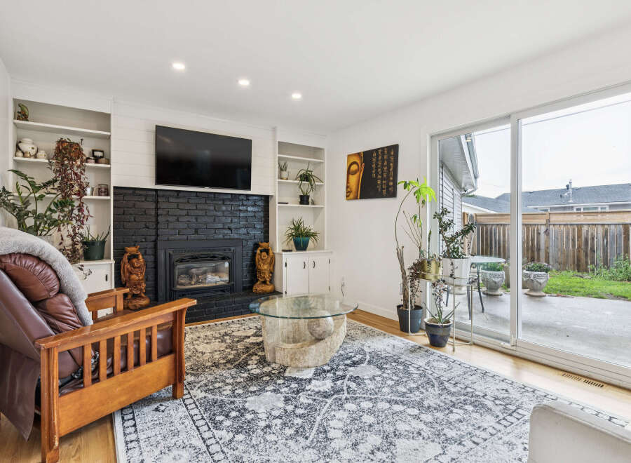 This inviting living room features a striking black brick fireplace as the focal point, complemented by built-in shelving perfect for displaying decor.