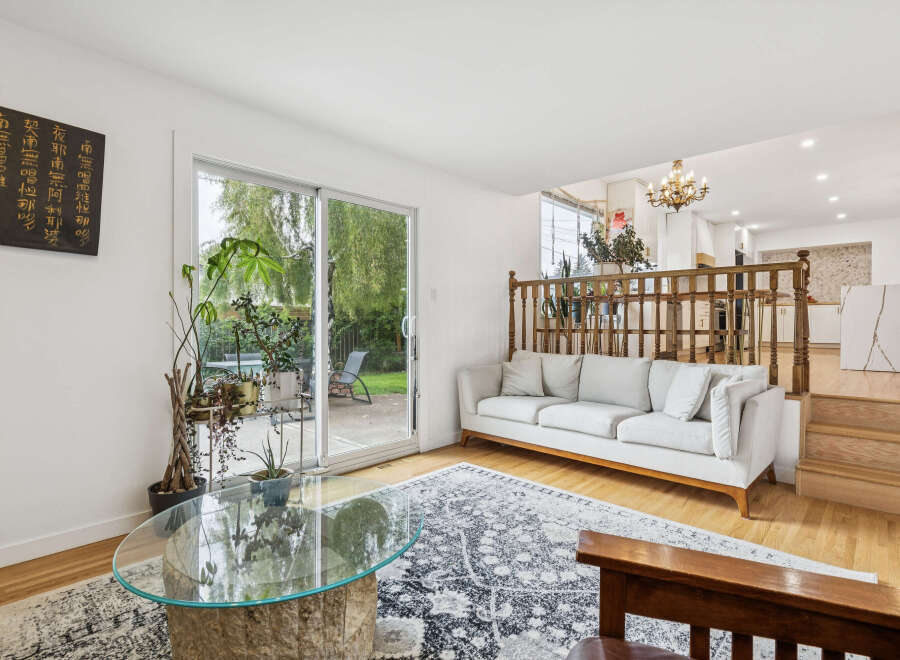 Step into this inviting living space featuring a comfortable white sofa, a unique stone coffee table, and a large sliding glass door that opens to a lush green backyard.