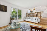 Step into this inviting living space featuring a comfortable white sofa, a unique stone coffee table, and a large sliding glass door that opens to a lush green backyard.