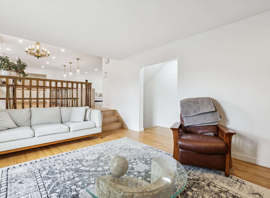 Step into this inviting living space featuring a plush white sofa and a rich brown leather armchair, perfect for relaxation.