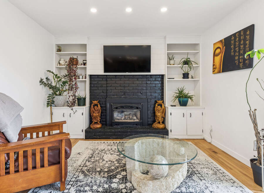 Cozy living room featuring a black brick fireplace with a mounted TV and built-in shelving.