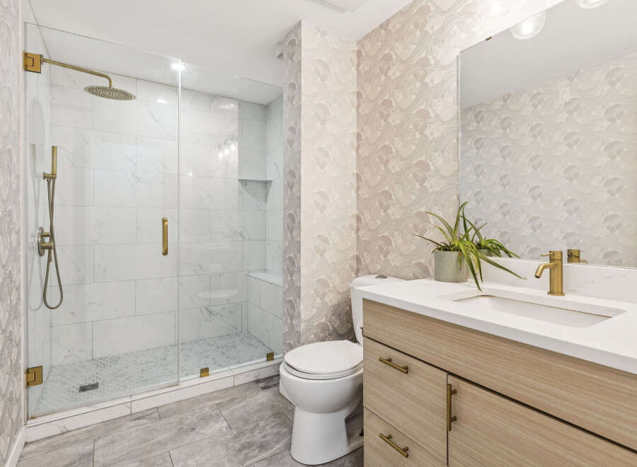 Experience luxury in this modern bathroom featuring a spacious glass-enclosed shower with marble tile and a rainfall showerhead.