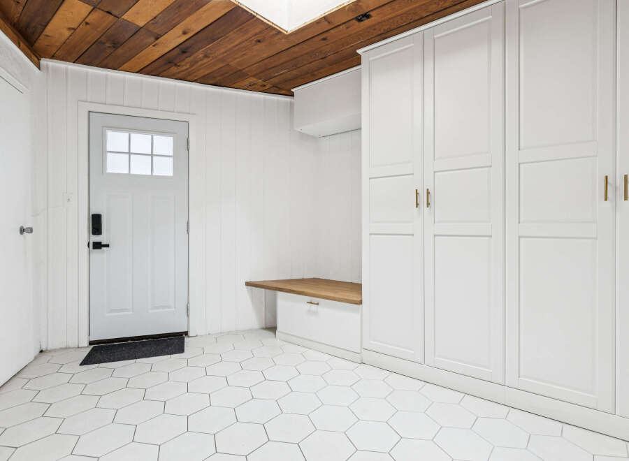 This entryway features a white paneled door with a glass window, leading into a space with white hexagonal floor tiles.