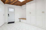 This entryway features a white paneled door with a glass window, leading into a space with white hexagonal floor tiles.