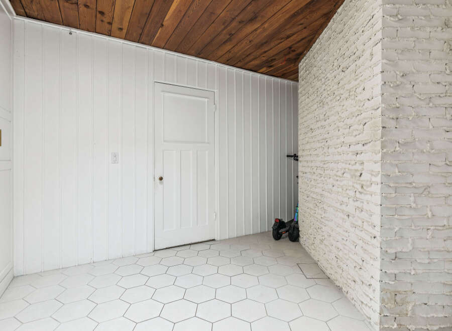 Discover this unique space featuring a rustic wooden ceiling and a charming white beadboard wall.