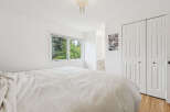 This bright and airy bedroom features a large window offering serene views of lush greenery.