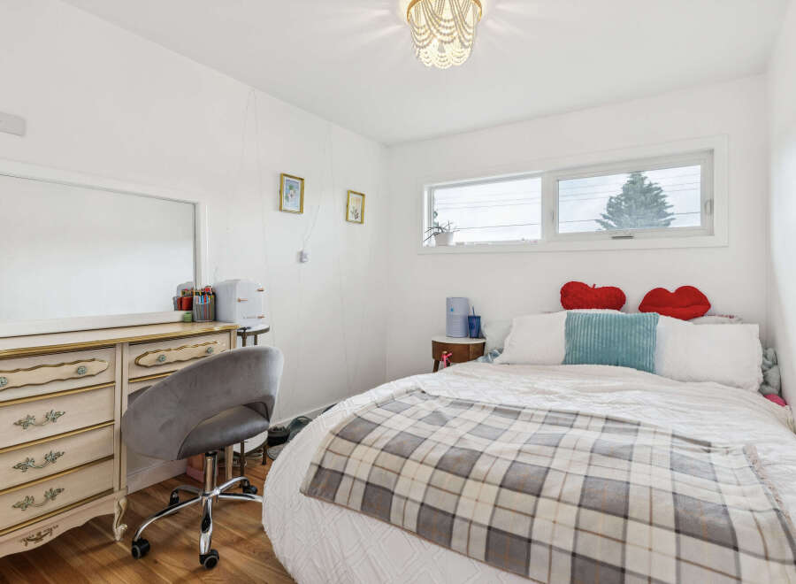 Discover this charming bedroom featuring a cozy bed adorned with a plaid blanket and decorative pillows.