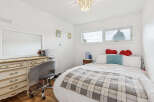 Discover this charming bedroom featuring a cozy bed adorned with a plaid blanket and decorative pillows.