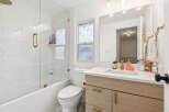This modern bathroom features a sleek design with marble-look tile walls and a glass shower enclosure.