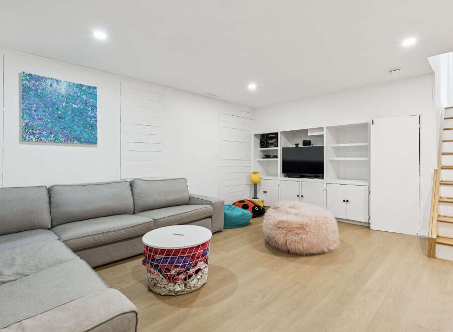 This modern living room features a spacious sectional sofa, a fluffy pink beanbag chair, and a unique woven storage ottoman.