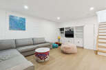 This modern living room features a spacious sectional sofa, a fluffy pink beanbag chair, and a unique woven storage ottoman.