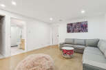 This modern living space features a comfortable grey sectional sofa complemented by a unique wire basket coffee table and a plush pink accent pouf.