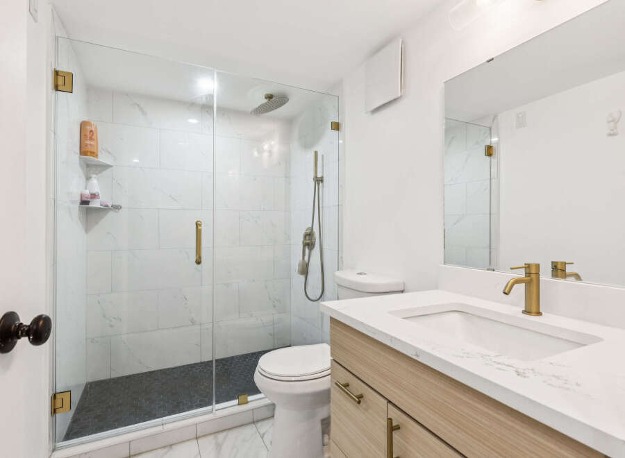 Experience modern luxury in this stunning bathroom featuring a spacious glass-enclosed shower with elegant marble tile and a sleek rainfall showerhead.