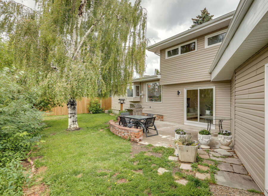 Enjoy outdoor living in this spacious backyard featuring a patio area perfect for entertaining, complete with a grill and dining set.