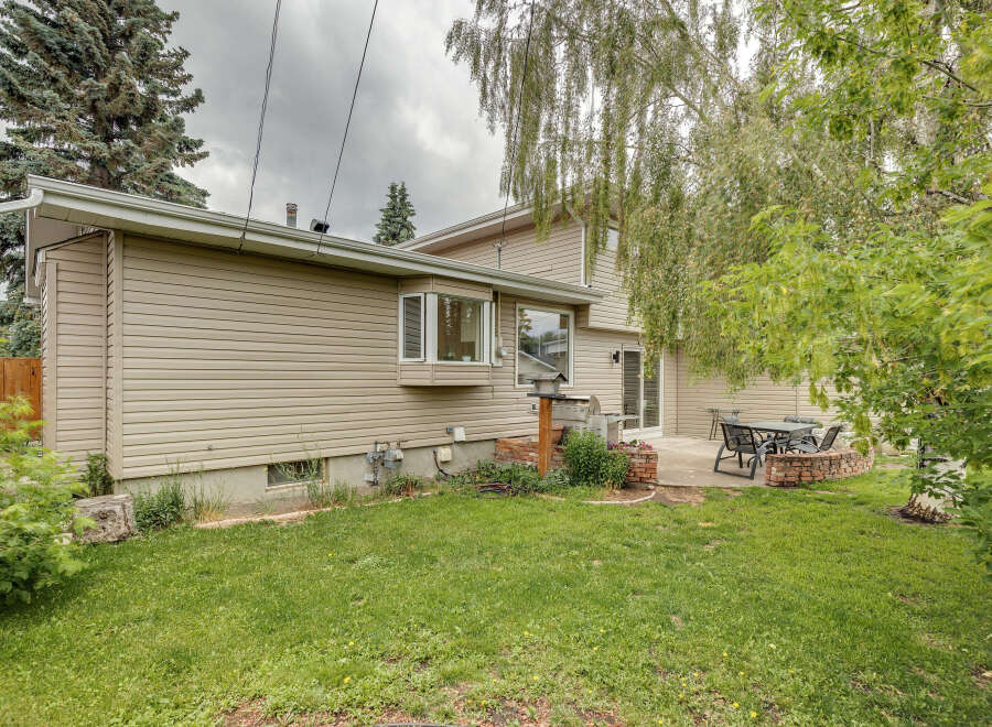 Enjoy outdoor living with this charming backyard featuring a patio, a built-in brick fire pit, and a grill area perfect for entertaining.