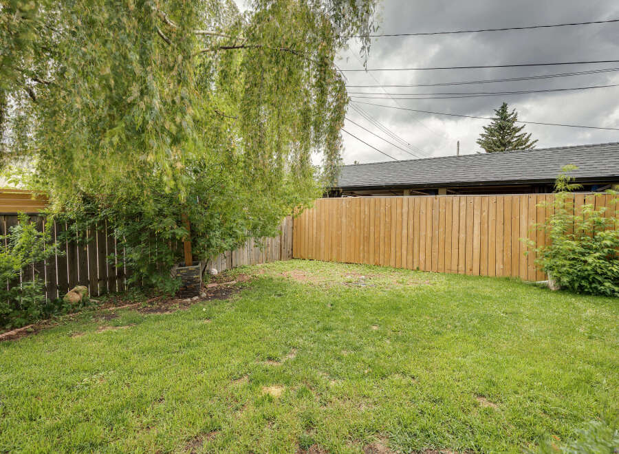 Enjoy outdoor living in this spacious backyard, complete with a lush green lawn and a newly fenced perimeter for privacy.