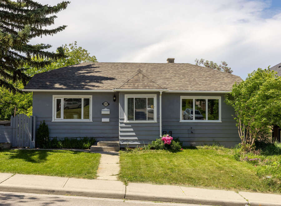 Charming grey bungalow featuring a well-maintained lawn and a welcoming front entrance.