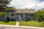 Charming grey bungalow featuring a well-maintained lawn and a welcoming front entrance.