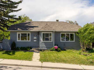 Charming grey bungalow featuring a well-maintained lawn and a welcoming front entrance.